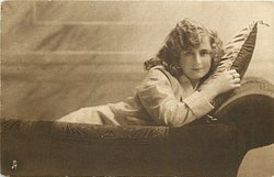 girl lying on couch, back of couch to front, facing right looking front, right hand on pillow