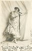 Image 1 - woman in low cut dress, stands in front of curtain, black ribbon tied to arm