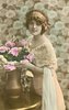 Image 1 - glamorous lady in dress with lace top & filmy shawl over her arm, bunch of roses in copper vase, looks at camera, left hand touches roses