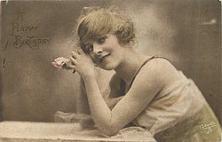 woman with fluffy hair faces left, looks up, rests her elbows on table, and rests her head on hands, one rose held in her clasped hand