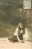 Image 1 - Mignon sits on ground, holding bag in her right hand, looking front
