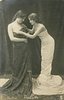 Image 1 - they face each other, girl on right adjusts dress of her partner, they both look down