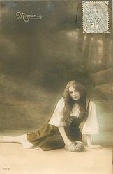 Mignon sits on ground, holding bag in her right hand, looking front