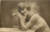 Image 1 - woman with fluffy hair faces left, looks up, rests her elbows on table, and rests her head on hands, one rose held in her clasped hand