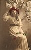 Image 1 - girl sits on stepladder, touching lilac overhead with her right hand & holding single rose on her lap with her left