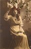 Image 2 - girl sits on stepladder, touching lilac overhead with her right hand & holding single rose on her lap with her left