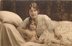 mother in bed with child, mother right & back, her right hand in front of childs chest, child sitting close to mothers right chest