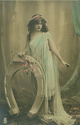 she stands erect by fantasy horseshoe holding it & flowers with her right hand