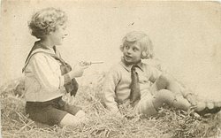 two boys play in straw, one aims toy pistol at the other