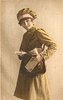 Image 1 - uniformed postlady delivering letters, faces left, looks forward, opens satchel with her left hand which also holds a letter, another letter in her right hand