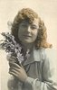 Image 2 - girl left profile, holds flowers to her right cheek, looks at camera