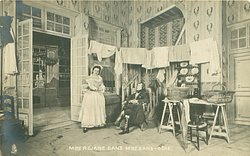 MME.REJANE DANS MME. SANS-GENE man seated dressed for out-doors, girl stands left in kitchen with washing hanging