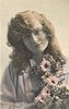 Image 1 - girl faces camera, holds flowers to her left chest, looks at camera