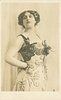 Image 4 - HAYGATE woman in elaborate dress with metallic breast plates, hand on hip