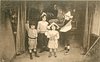 Image 1 - four children in room stand facing front, boy on right plays trumpet, boy & girl front wave pretend swords