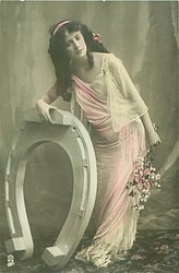 she leans over fantasy horseshoe holding it with her right hand, flowers in her left ahnd