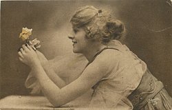 woman with fluffy hair leaning over table looking at roses held between both hands