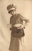 Image 1 - uniformed postlady delivering letters, faces left, looks down, opens satchel with her left hand, another letter in her right hand