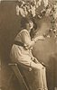 Image 1 - girl sits on stepladder facing right, looking front, touching lilac in front of her with her right hand & holding single rose on her lap with her left