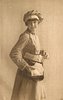 Image 2 - uniformed postlady delivering letters, faces right, looks forward, opens satchel with her left hand, letters in her right