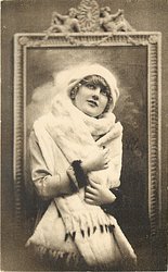 pretty girl with ermine fur & cap posed in front of framed mirror, she faces front looks up, both hands hold fur in front of her