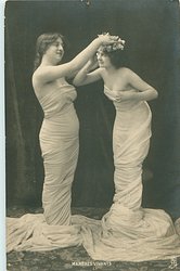 they face each other, girl on left adjusts flowers on the head of her partner