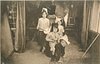Image 1 - four children in room, 2 boys front one riding on others back, 2 girls behind, one playing drum