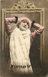 pretty girl with ermine fur & cap posed in front of framed mirror, she faces front looks up, hands behind head