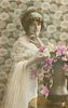 Image 1 - glamorous lady in dress with lace top & filmy shawl over her arm, bunch of roses in copper vase, looks at camera but body turned to right, right hand touches flowers, left hand under chin