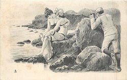 man with camera peers over rocks at two girls caressing