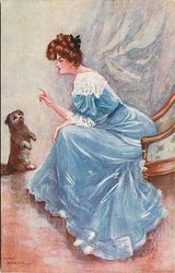 pretty lady in blue dress holds finger out to sitting dog