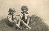 Image 1 - two boys play in straw, both sit cross-legged, looking forward