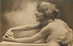 woman with flufy hair reaches arms across table left, rose in between her hands