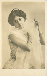 woman with filmy wrap around shoulders, right hand on her left shoulder