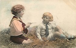 two boys play in straw,one aims toy pistol at the other