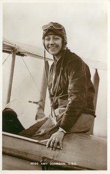 seated on back edge of cockpit, smiling