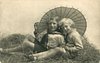 Image 1 - two boys play in straw, looking forward, parasol behind, handle between boys
