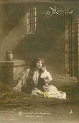 OUI, C'EST LUI PLUS DE PRISON, PLUS DE CHAINES! Marguerite sits on bed of twigs in prison, facing front, left hand raised to her ear